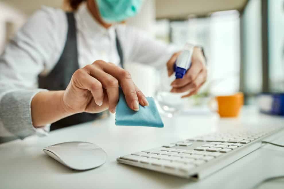 Close Up Of Businesswoman Disinfecting Computer Keyboard In The