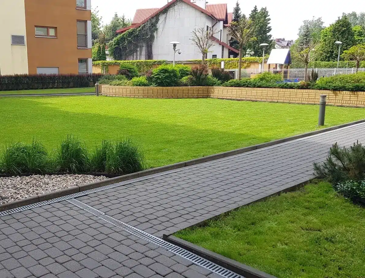 Zadbany teren osiedla mieszkaniowego: skoszony trawnik i czyste chodniki